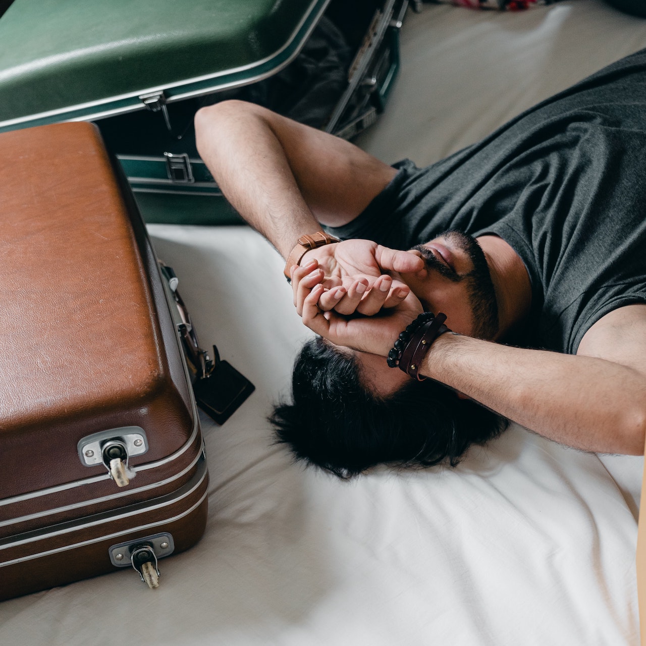 Man lying on bed with suitcases
