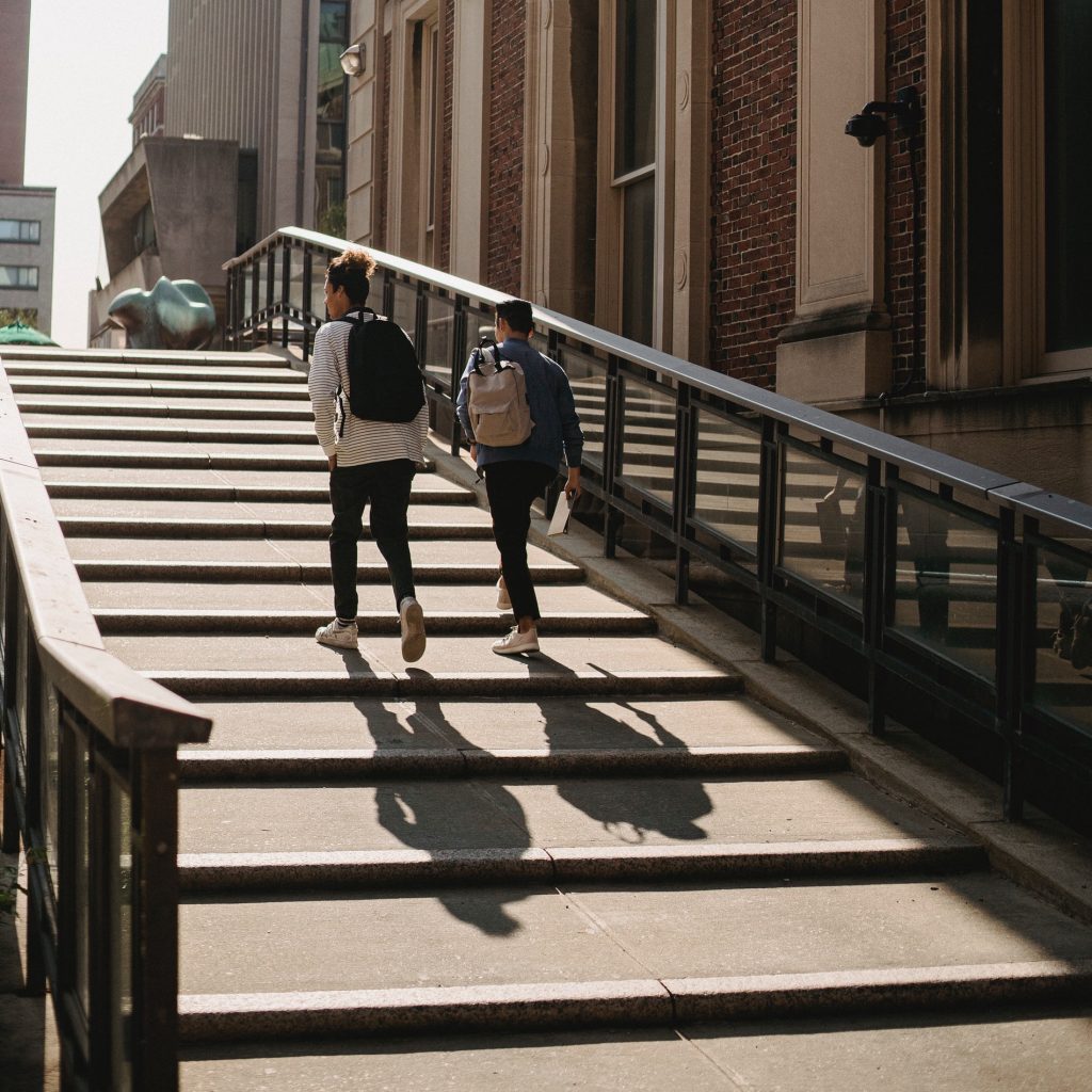 Young men walking up stairs in sunlight